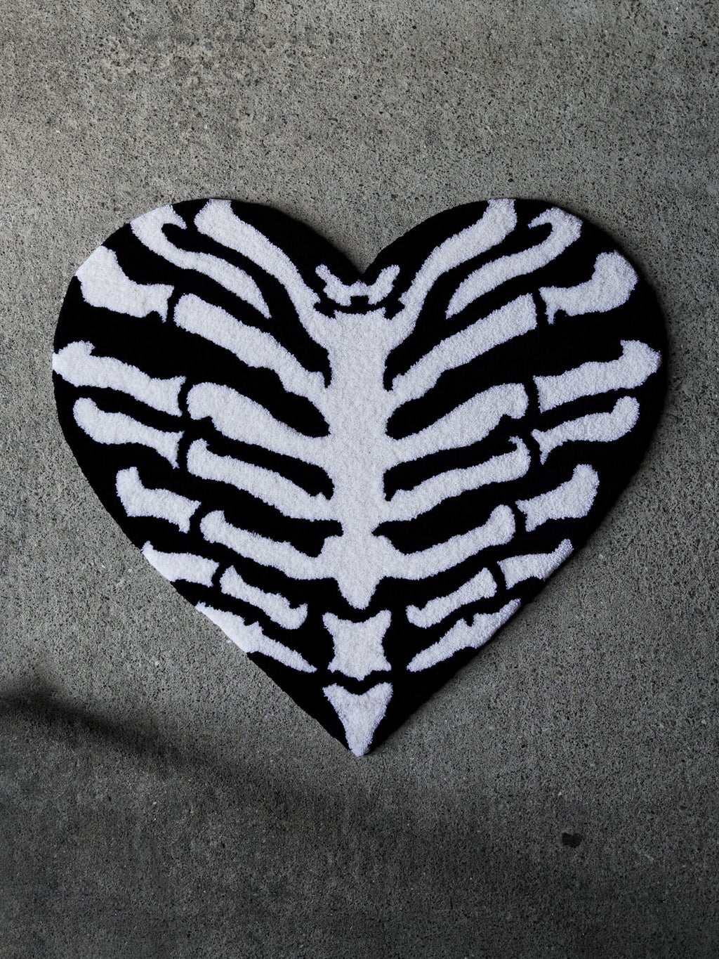 The Ribcage Heart Rug by Void Rugs. A bold hand-tufted rug featuring a ribcage inside a heart silhouette.