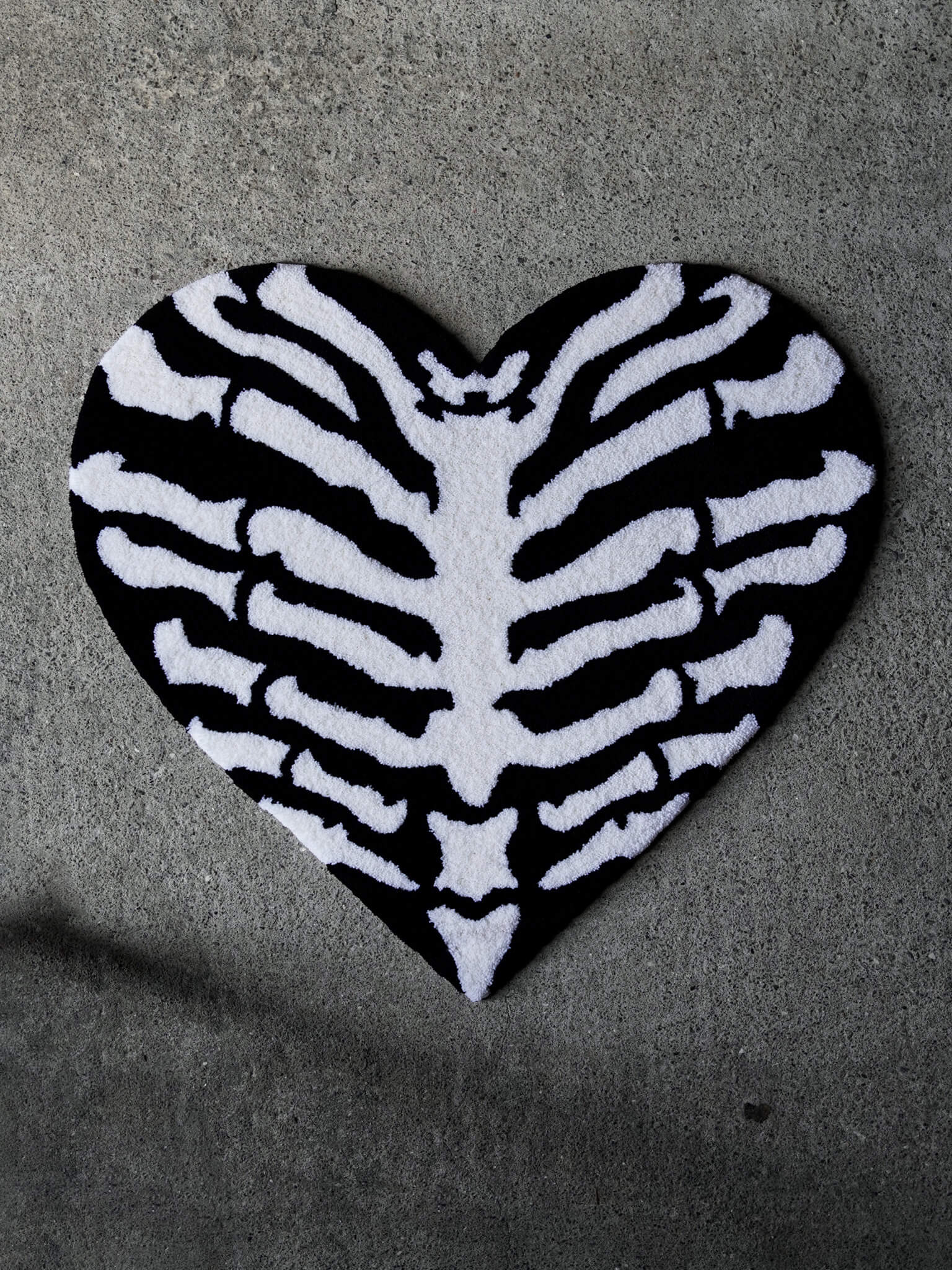 The Ribcage Heart Rug by Void Rugs. A bold hand-tufted rug featuring a ribcage inside a heart silhouette.