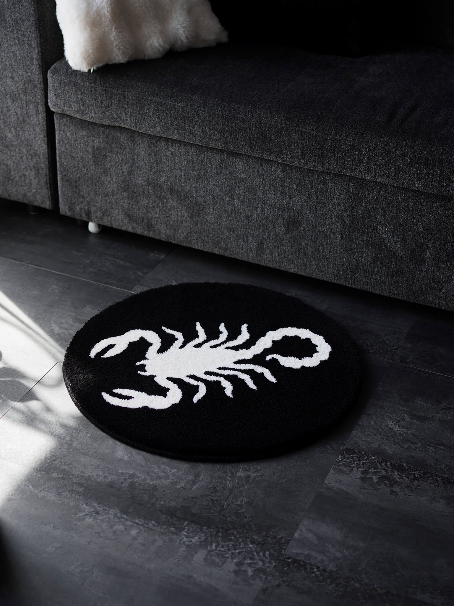 Scorpion circle rug grounding a dark living space, showcasing its striking presence in an alternative home.