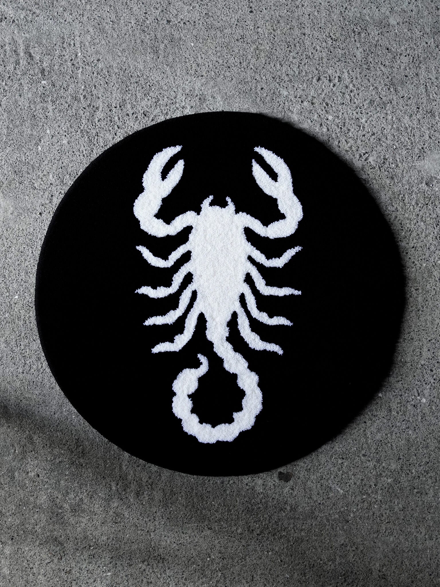 The Scorpion Circle Rug. A bold, stark-white scorpion icon against a solid black background.