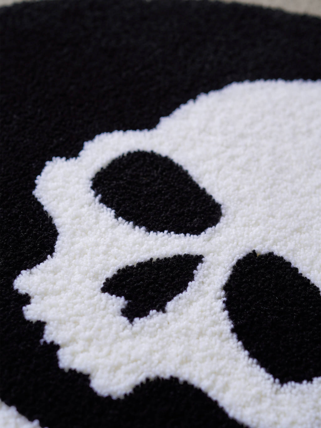 Macro detail shot of the Skull and Crossbones rug, emphasizing the high-quality yarn and stark contrast.