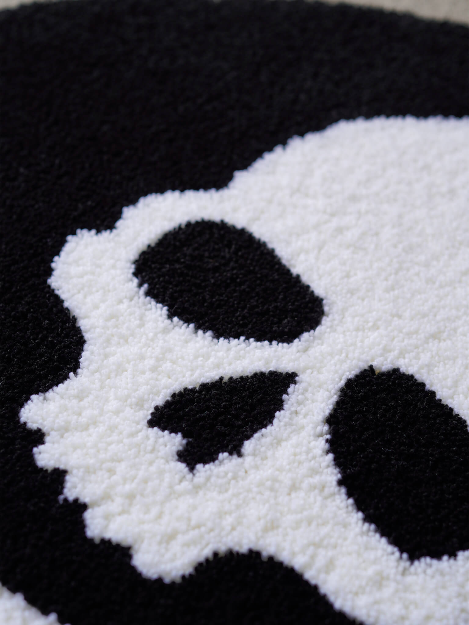 Macro detail shot of the Skull and Crossbones rug, emphasizing the high-quality yarn and stark contrast.
